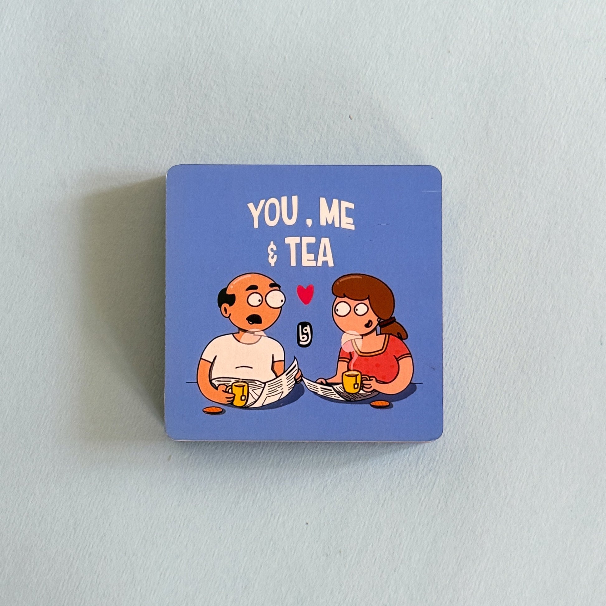 Square blue magnet with cartoon characters and text 'You, Me & Tea' on a light gray background