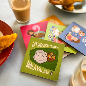 Colorful coasters with illustrations and text on a table with food and drinks.